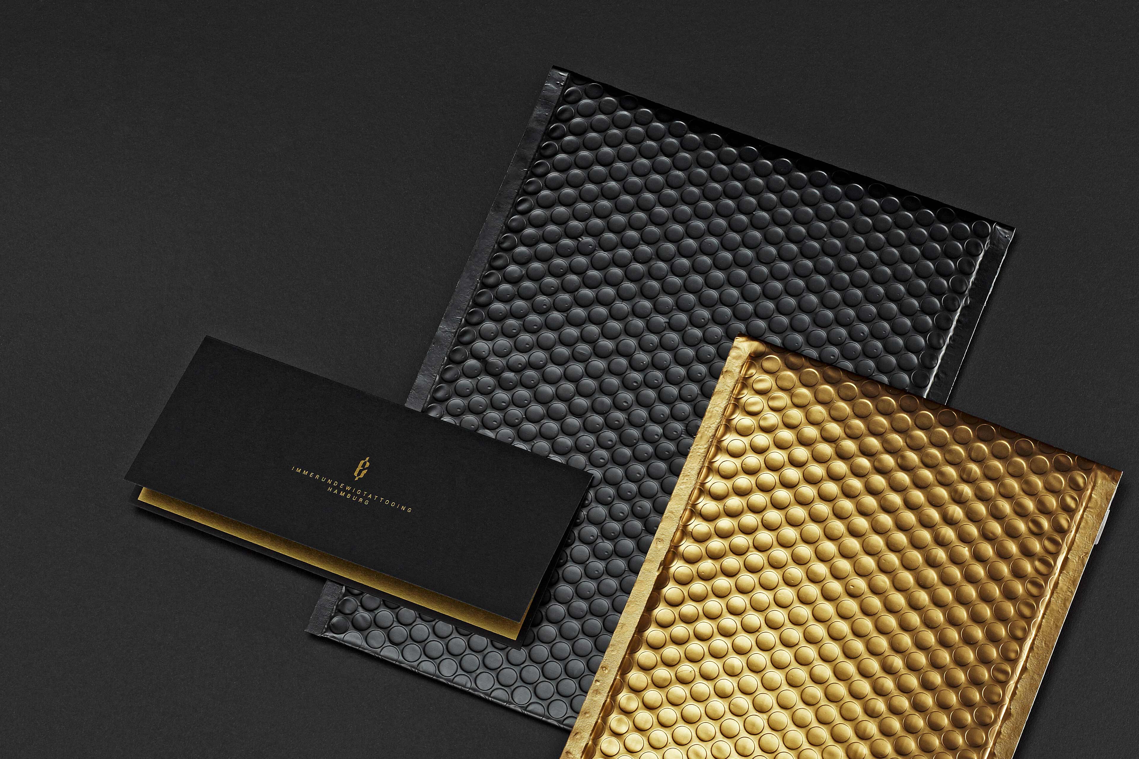 Schwarzen und goldene Luftpolsterfolien liegen auf einem schwarzen Karton.