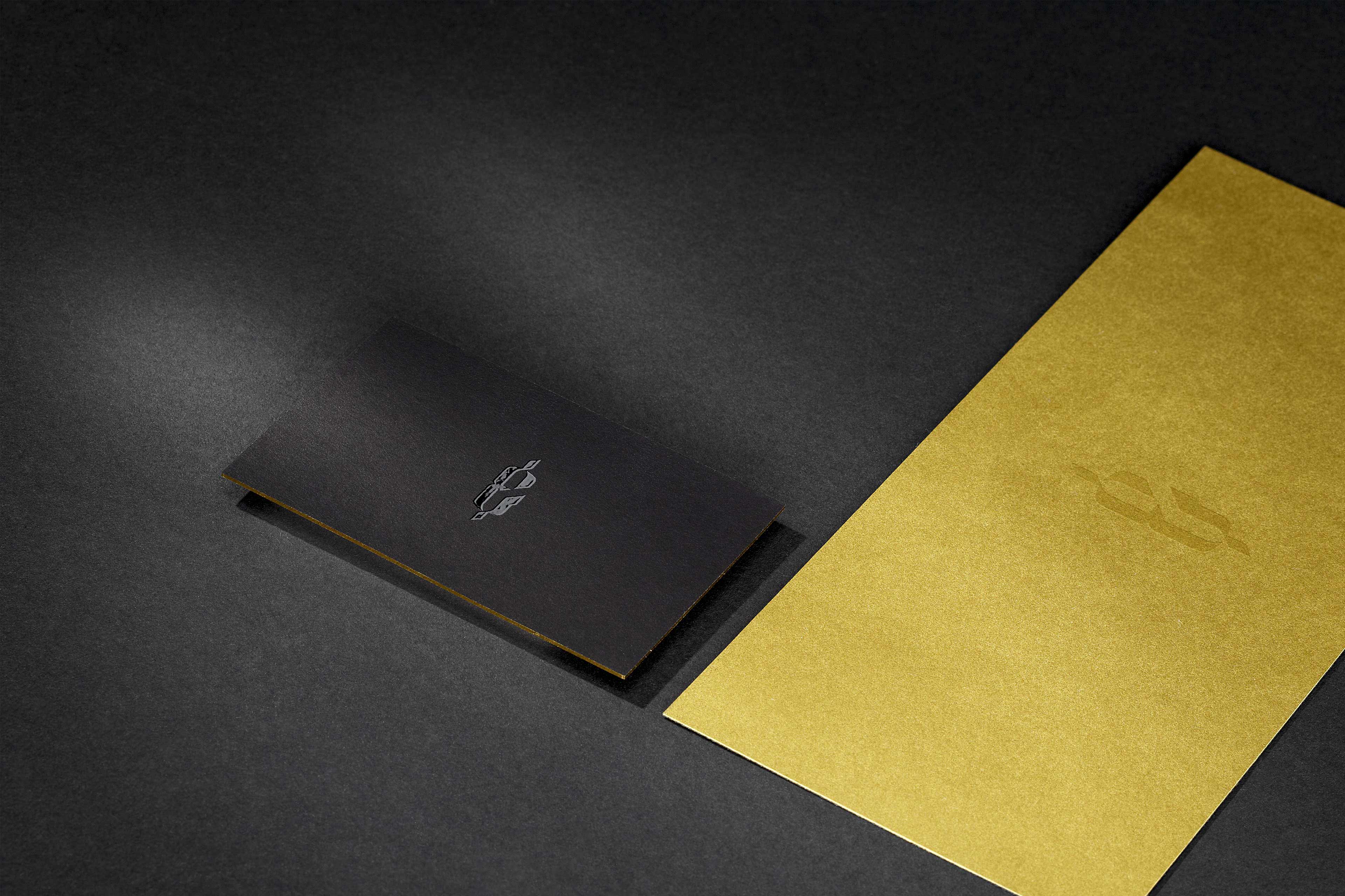 Eine schwarze Visitenkarte neben einer goldenen Gutscheinkarte. Beide sind mit einem UV Lacke veredelt.